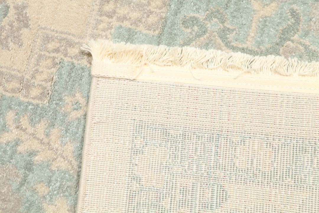 Cremefarvet og lyseblåt tæppe med et traditionelt mønstret design