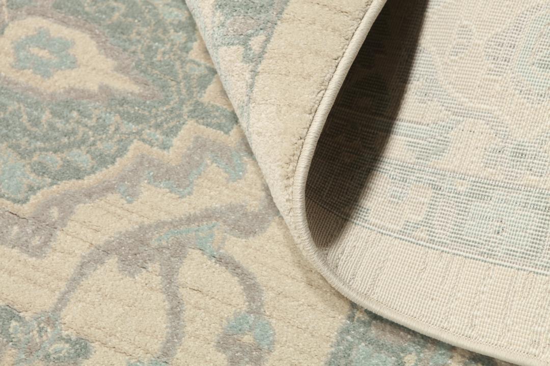 Cremefarvet og lyseblåt tæppe med et traditionelt mønstret design