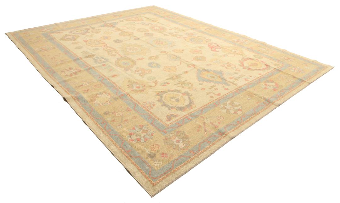 Een handgeknoopt Usak-tapijt uit Turkije met een beige veld en kleurrijke bloemmotieven.