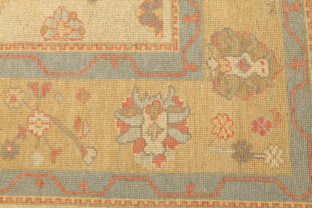 Een handgeknoopt Usak-tapijt uit Turkije met een beige veld en kleurrijke bloemmotieven.