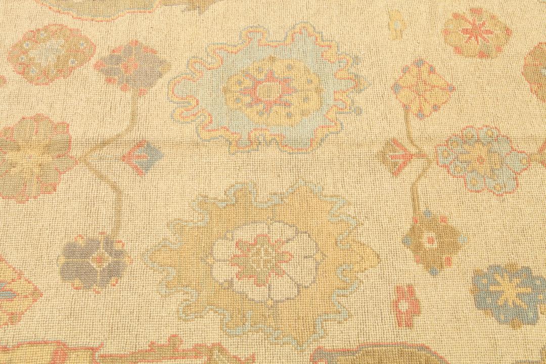 Een handgeknoopt Usak-tapijt uit Turkije met een beige veld en kleurrijke bloemmotieven.