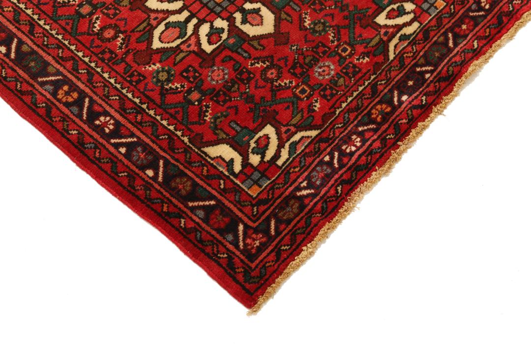 Un long tapis couloir Hosseinabad noué à la main, provenant du Moyen-Orient, arborant un fond rouge vibrant et des motifs floraux détaillés.