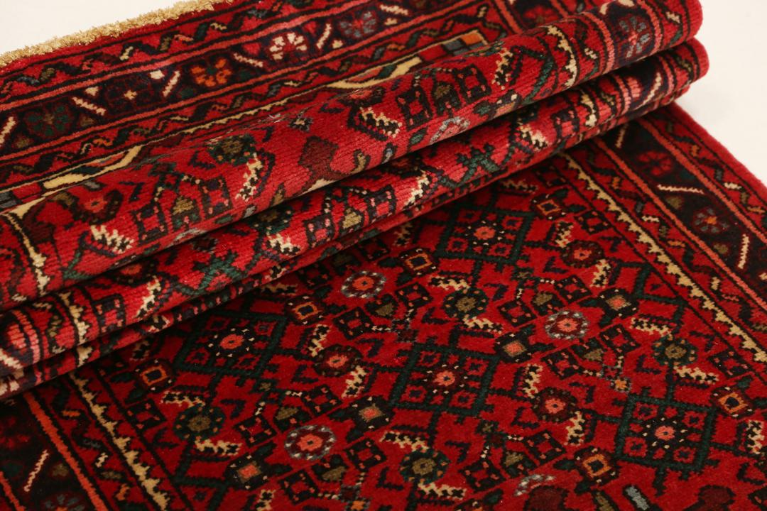 Un long tapis couloir Hosseinabad noué à la main, provenant du Moyen-Orient, arborant un fond rouge vibrant et des motifs floraux détaillés.