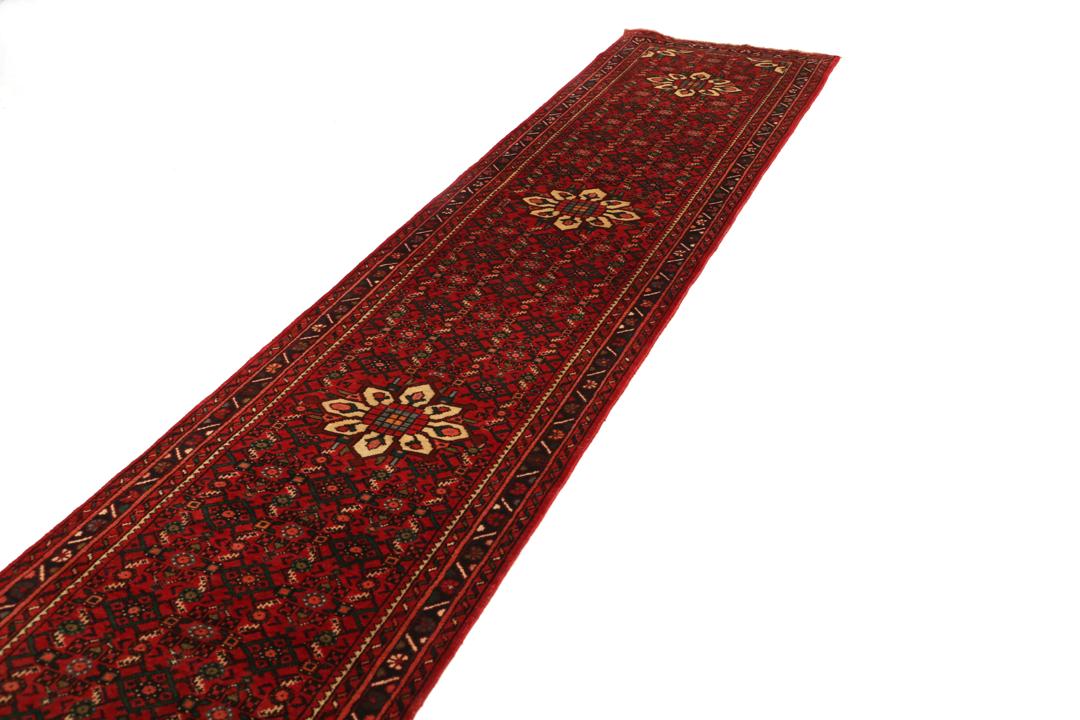 Un long tapis couloir Hosseinabad noué à la main, provenant du Moyen-Orient, arborant un fond rouge vibrant et des motifs floraux détaillés.