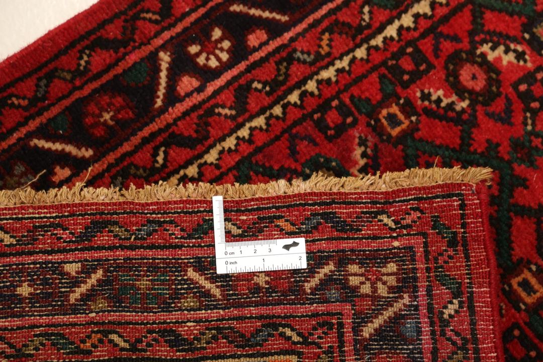 Un long tapis couloir Hosseinabad noué à la main, provenant du Moyen-Orient, arborant un fond rouge vibrant et des motifs floraux détaillés.