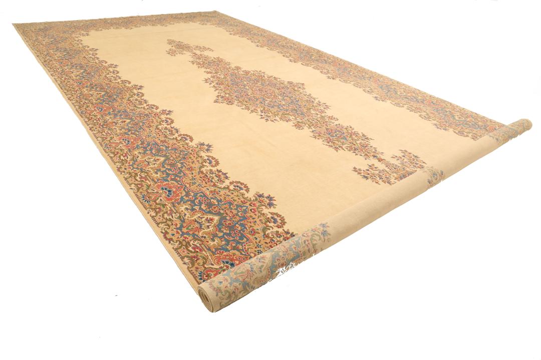 Large Kerman rug from the Middle East featuring a central floral medallion in beige, blue, and pink tones.