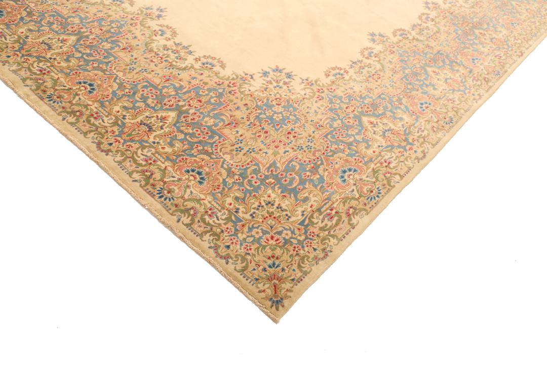 Large Kerman rug from the Middle East featuring a central floral medallion in beige, blue, and pink tones.