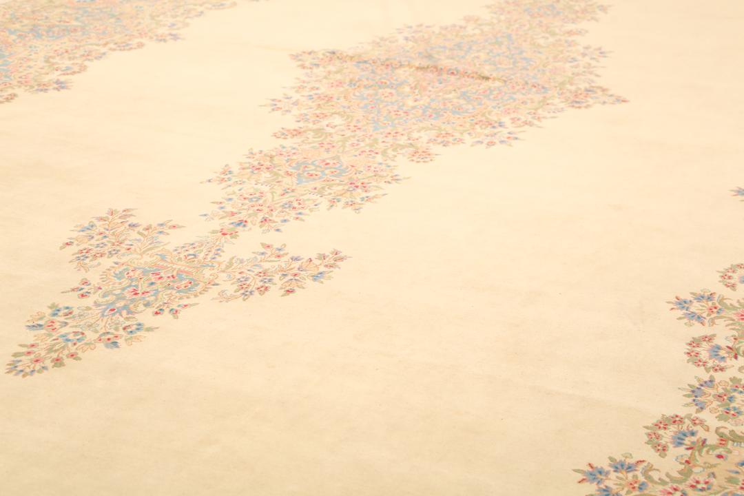 Large Kerman rug from the Middle East featuring a central floral medallion in beige, blue, and pink tones.