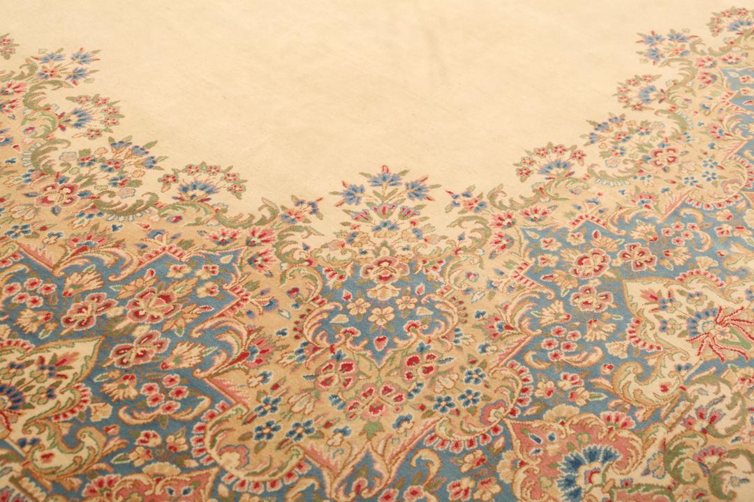 Large Kerman rug from the Middle East featuring a central floral medallion in beige, blue, and pink tones.