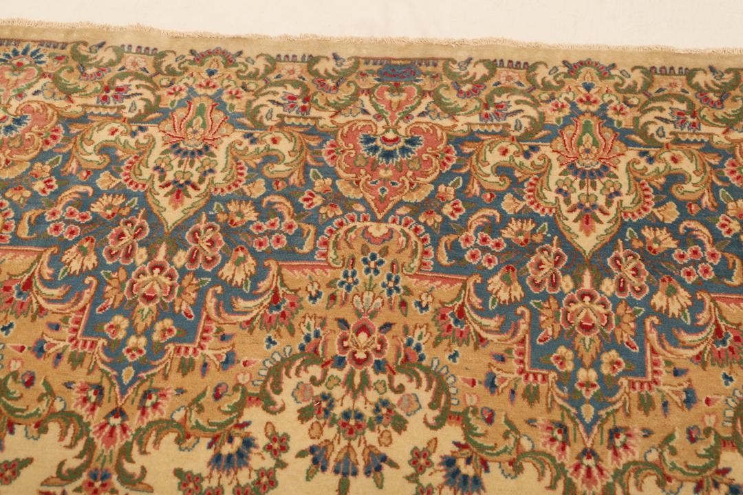 Large Kerman rug from the Middle East featuring a central floral medallion in beige, blue, and pink tones.