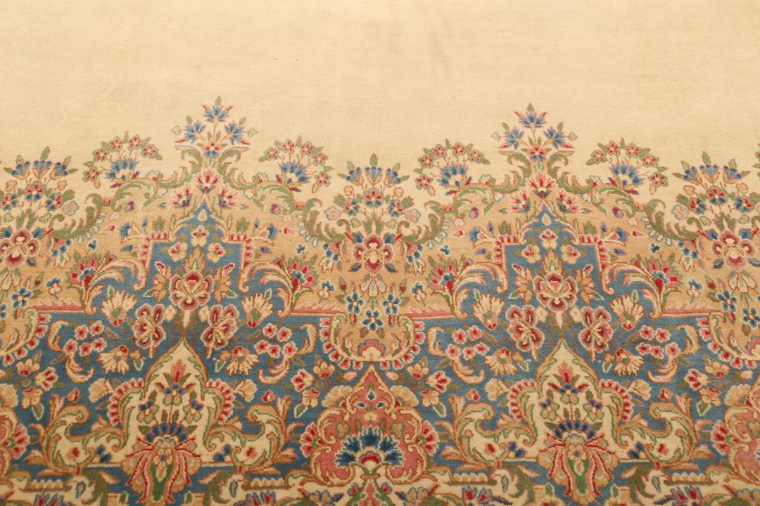Large Kerman rug from the Middle East featuring a central floral medallion in beige, blue, and pink tones.