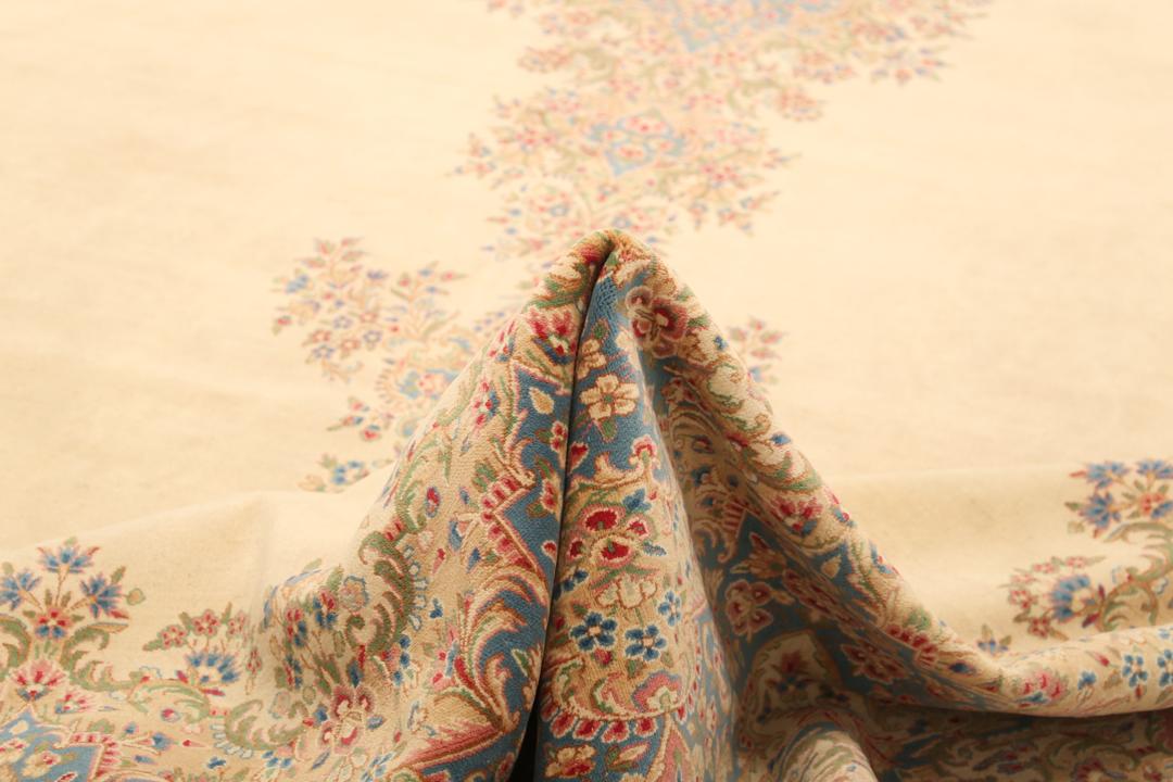 Large Kerman rug from the Middle East featuring a central floral medallion in beige, blue, and pink tones.