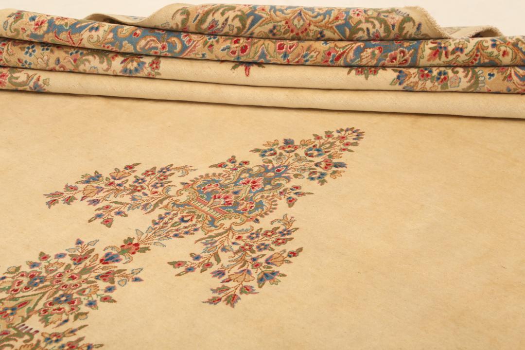 Large Kerman rug from the Middle East featuring a central floral medallion in beige, blue, and pink tones.