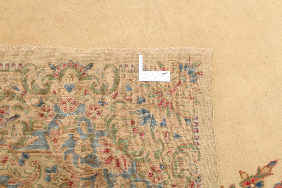Large Kerman rug from the Middle East featuring a central floral medallion in beige, blue, and pink tones.