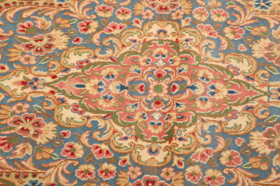 Large Kerman rug from the Middle East featuring a central floral medallion in beige, blue, and pink tones.