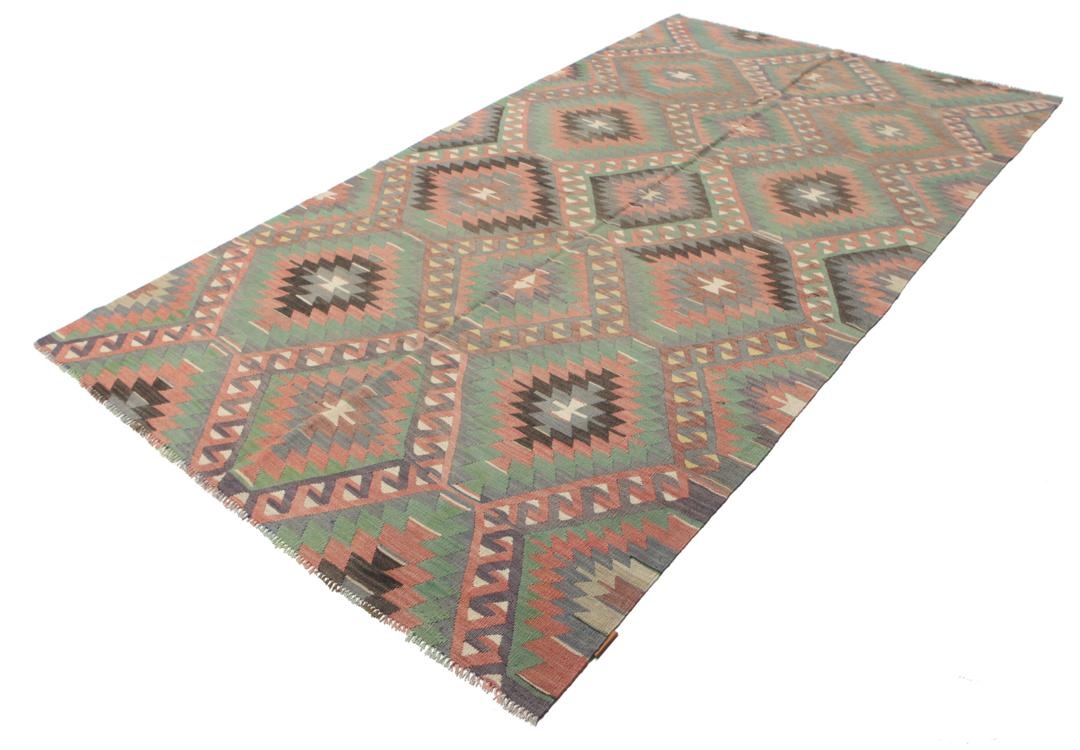 Een vintage Turks Kelim-tapijt met een geometrisch patroon in groene, bruine en rode tinten.