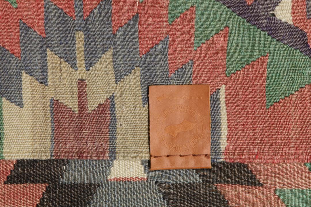 Een vintage Turks Kelim-tapijt met een geometrisch patroon in groene, bruine en rode tinten.