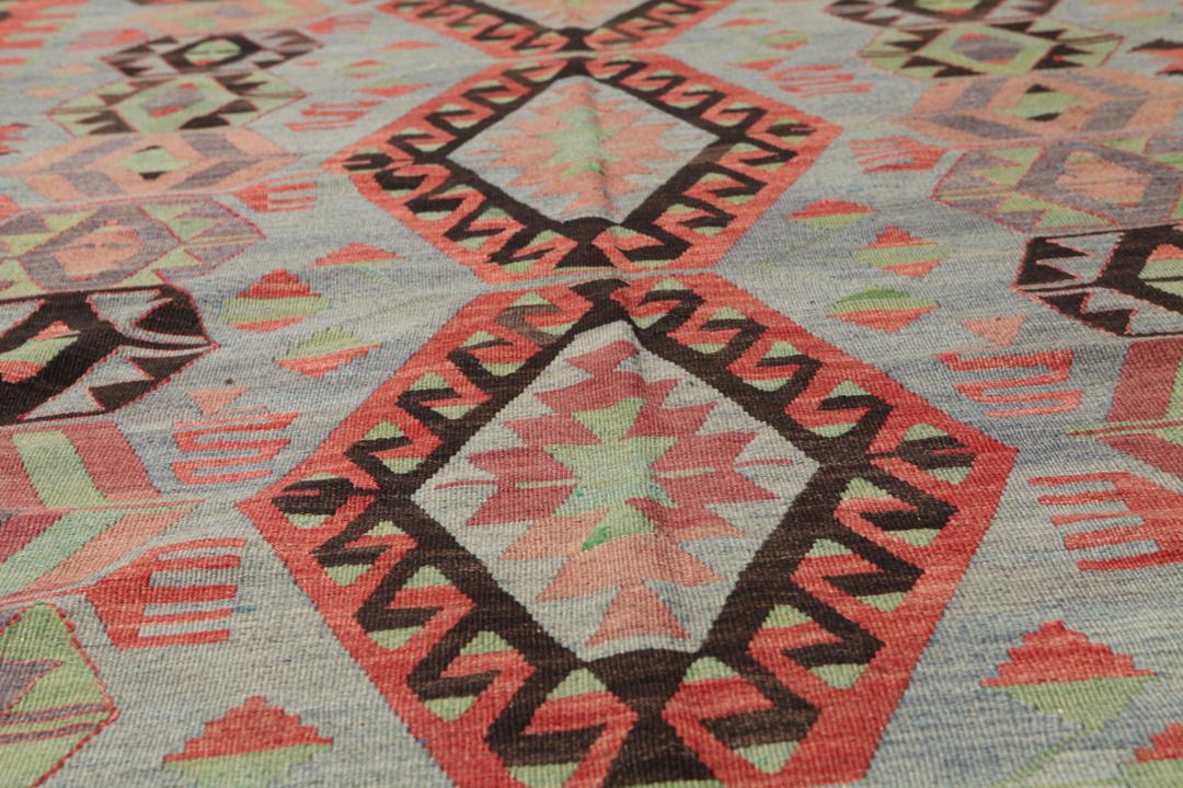 Een groot rechthoekig vintage Kelim-tapijt uit Turkije met geometrische diamantmotieven in rood, groen en grijs.