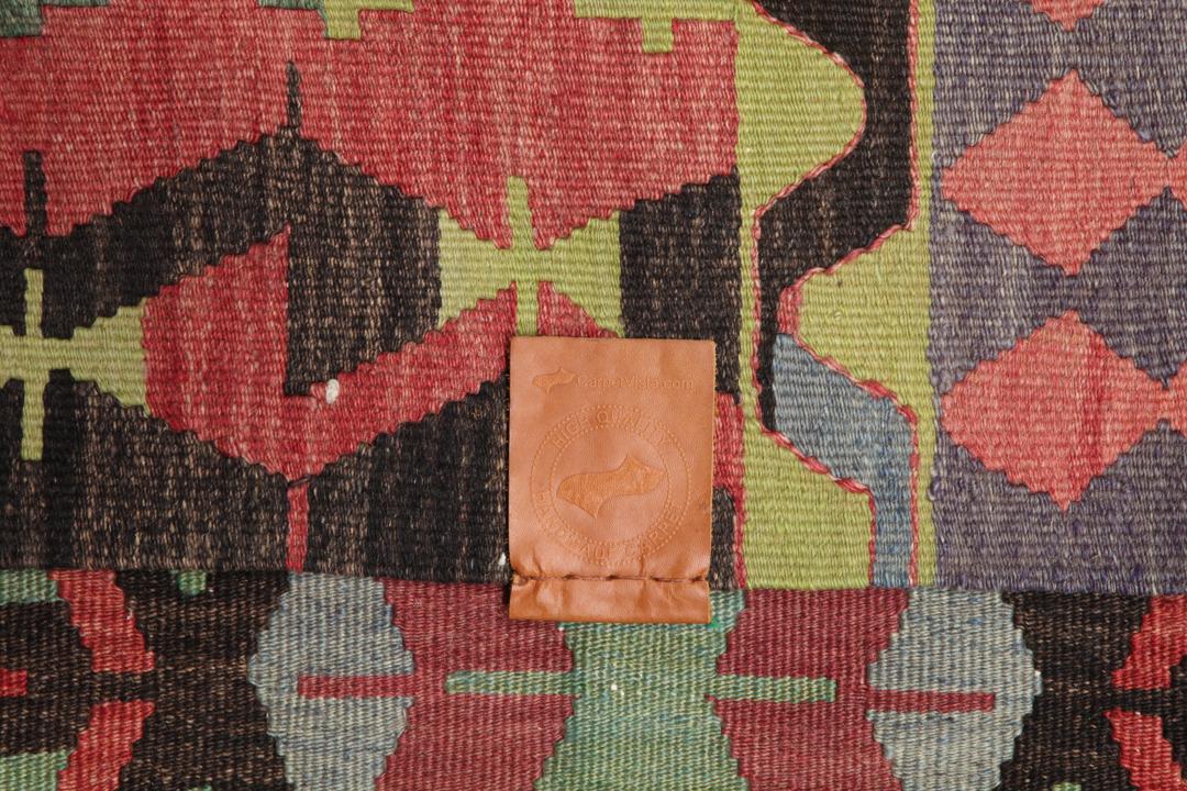 Een groot rechthoekig vintage Kelim-tapijt uit Turkije met geometrische diamantmotieven in rood, groen en grijs.