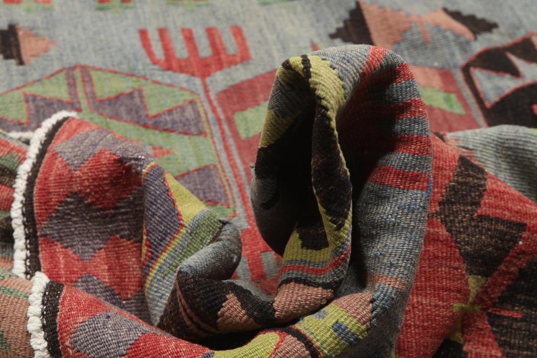 Een groot rechthoekig vintage Kelim-tapijt uit Turkije met geometrische diamantmotieven in rood, groen en grijs.