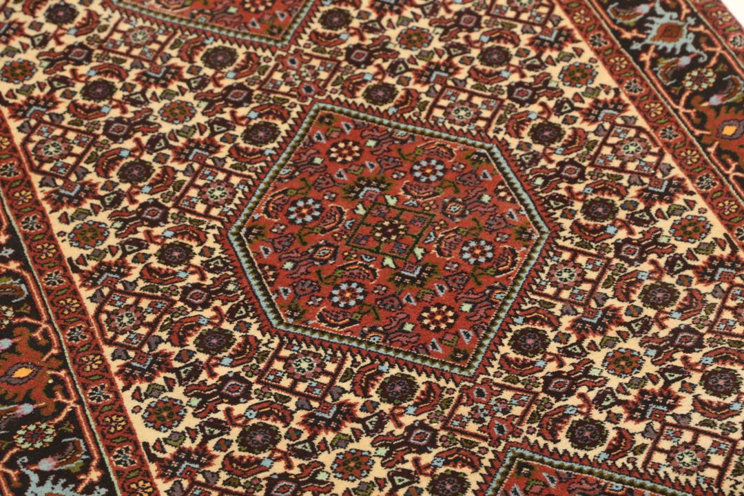 Een met de hand geknoopte loper uit het Midden-Oosten in de stijl van Bidjar met een rood en beige geometrisch patroon.