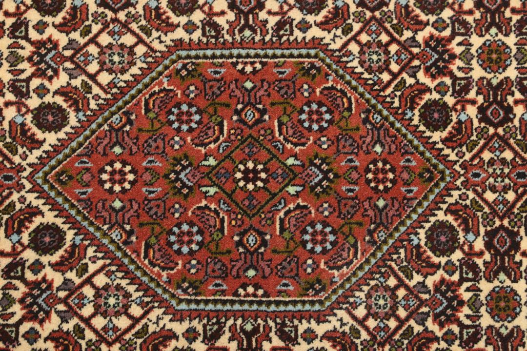 Een met de hand geknoopte loper uit het Midden-Oosten in de stijl van Bidjar met een rood en beige geometrisch patroon.