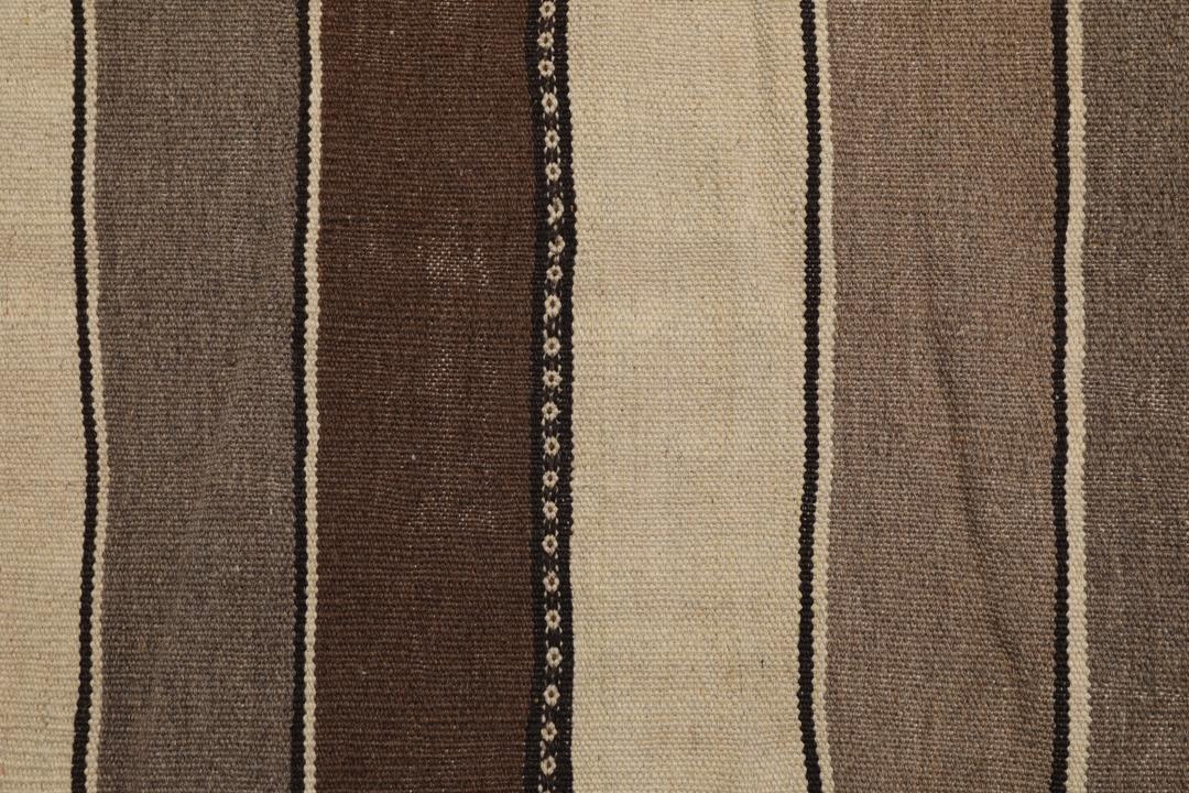 Et håndvævet kelimtæppe fra Mellemøsten med vandrette brune og beige striber.