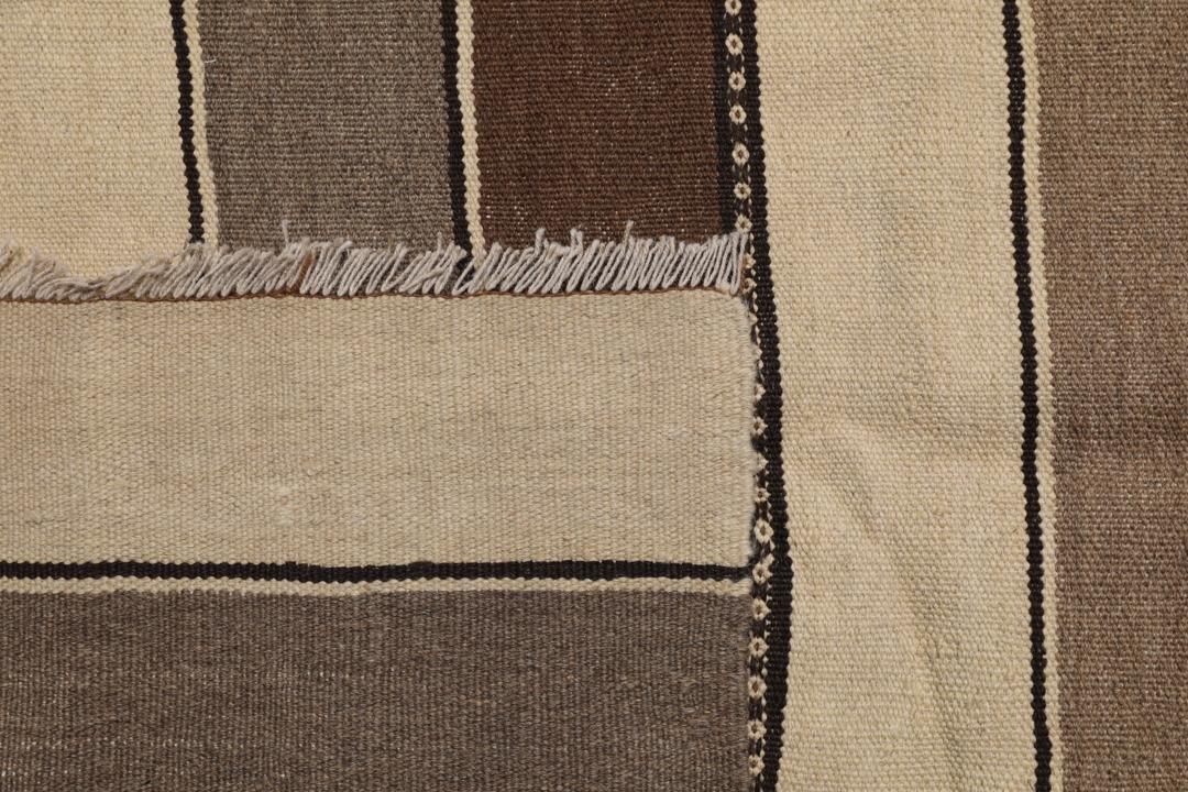 Et håndvævet kelimtæppe fra Mellemøsten med vandrette brune og beige striber.