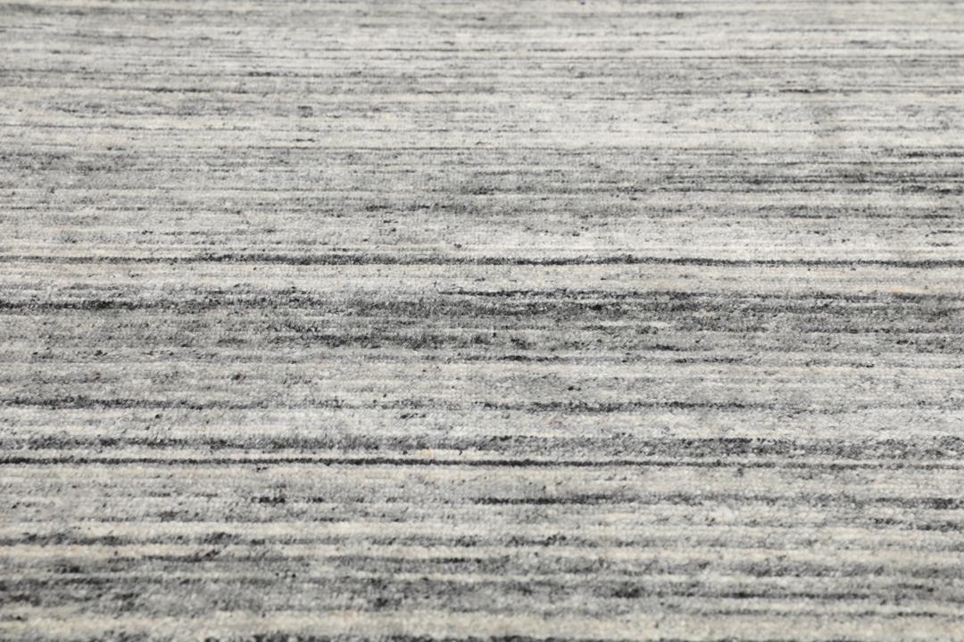 Een getextureerd grijs wollen tapijt met subtiele horizontale lijnen
