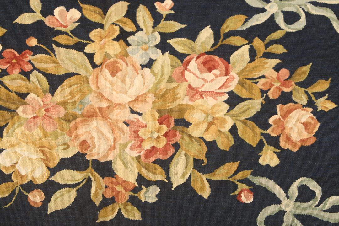 Een handgeweven Chinees tapijt met bloemmotieven op een donkerblauwe achtergrond
