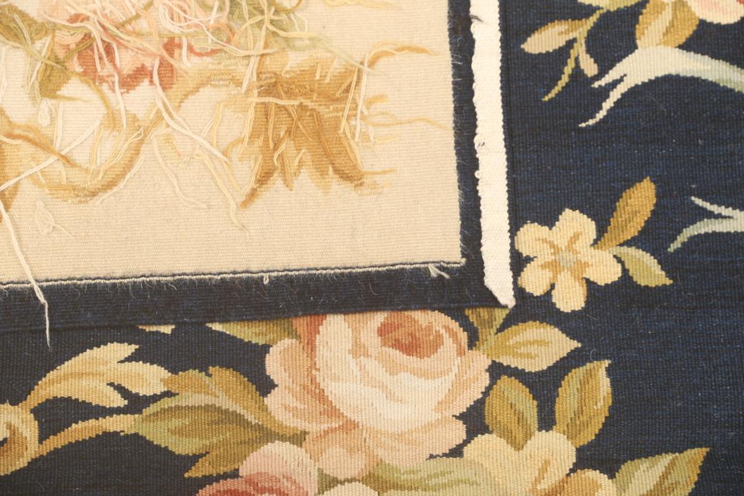 Een handgeweven Chinees tapijt met bloemmotieven op een donkerblauwe achtergrond