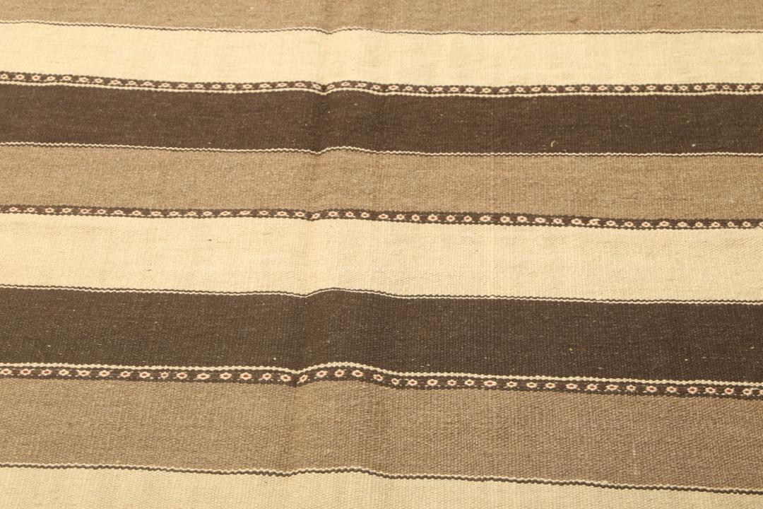 Et håndvævet mellemostligt kelimtæppe med vandrette brune og beige striber.