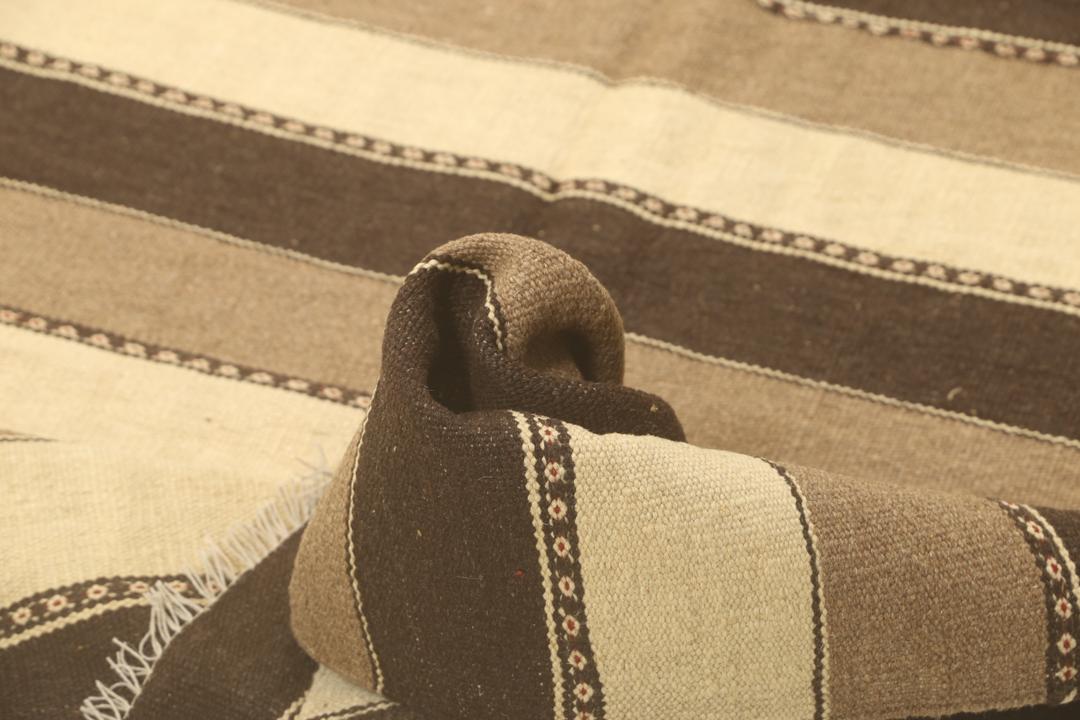 Et håndvævet mellemostligt kelimtæppe med vandrette brune og beige striber.