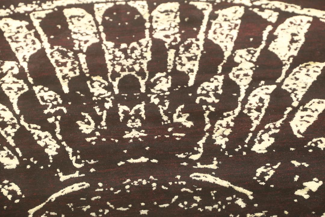 Un tapis moderne noué à la main originaire d'Inde avec un grand motif circulaire doré et noir.