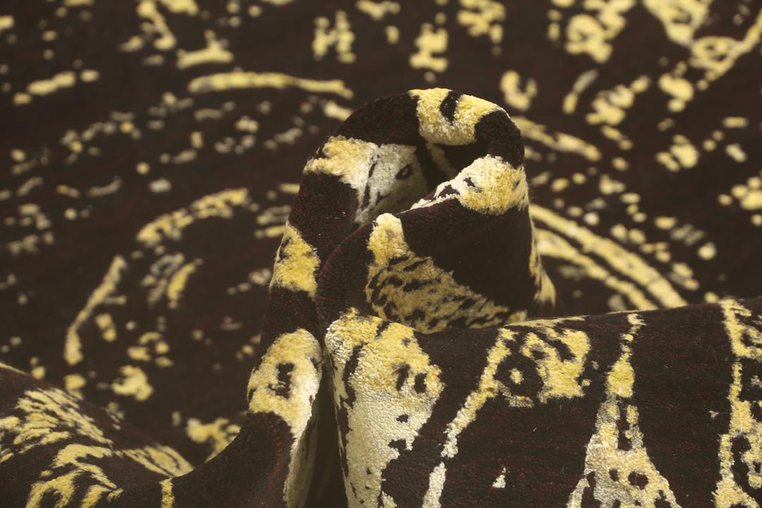 Un tapis moderne noué à la main originaire d'Inde avec un grand motif circulaire doré et noir.