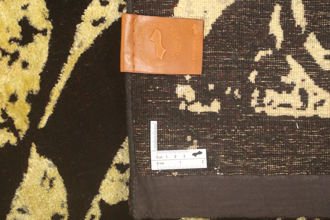 Un tapis moderne noué à la main originaire d'Inde avec un grand motif circulaire doré et noir.