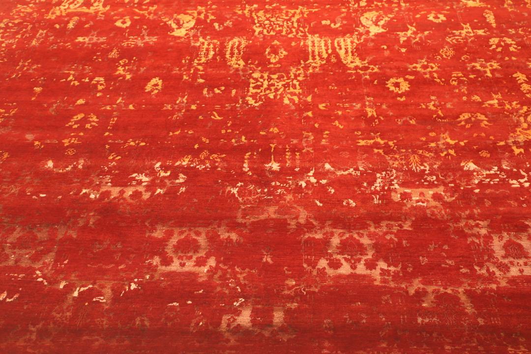 Een groot, rechthoekig handgeknoopt vloerkleed uit India met een levendig rood veld en organische gouden details.
