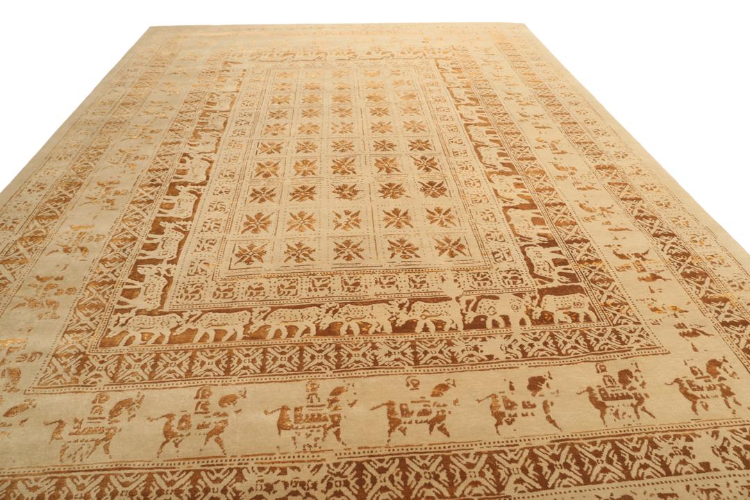 Et stort rektangulært indisk tæppe med en beige flade og indviklede gyldne mønstre.