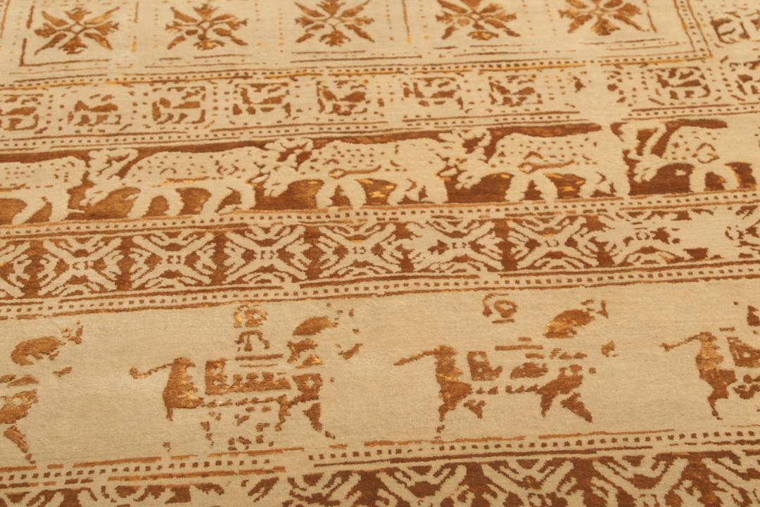 Et stort rektangulært indisk tæppe med en beige flade og indviklede gyldne mønstre.