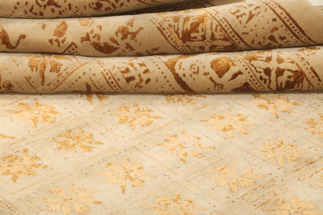 Et stort rektangulært indisk tæppe med en beige flade og indviklede gyldne mønstre.