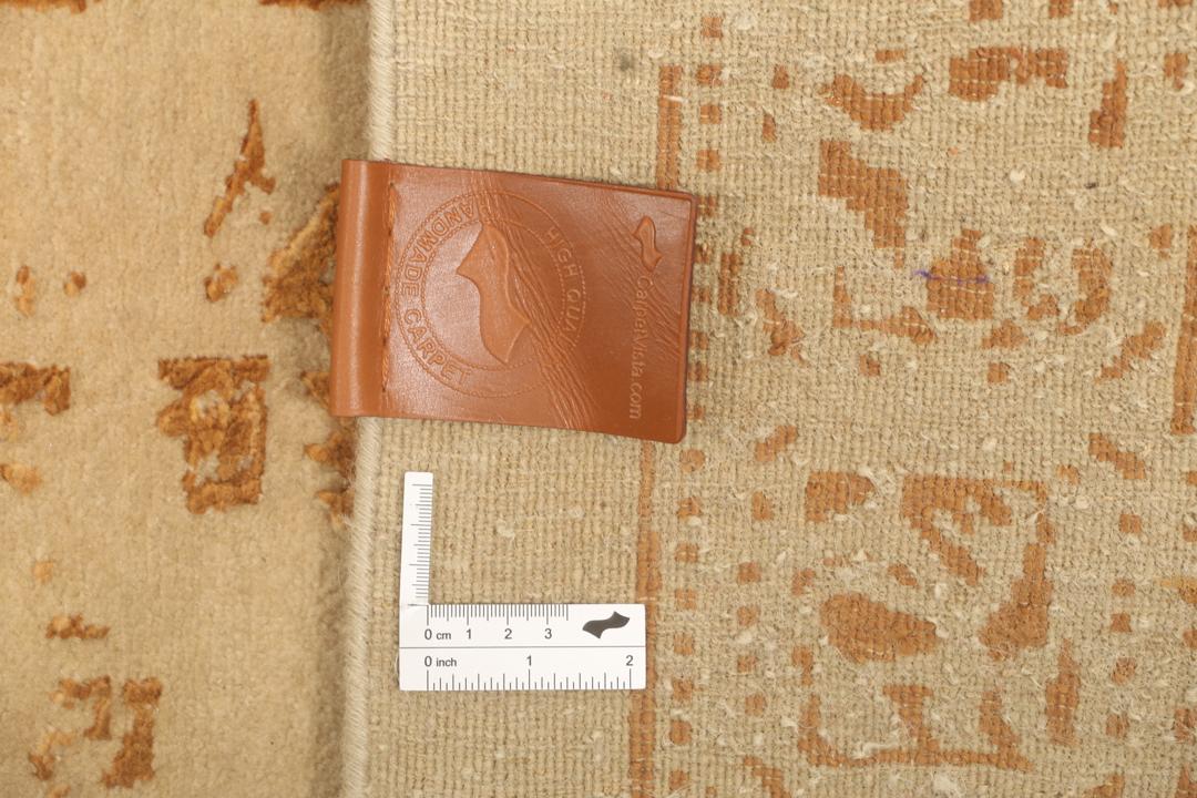 Et stort rektangulært indisk tæppe med en beige flade og indviklede gyldne mønstre.