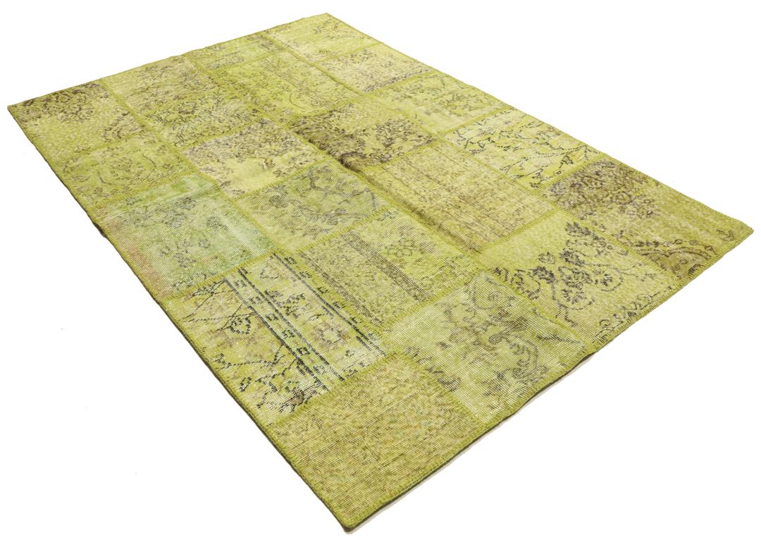 Een patchwork vloerkleed uit Turkije met een lichtgroen en bruin vintage design.