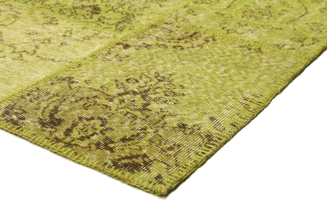 Een patchwork vloerkleed uit Turkije met een lichtgroen en bruin vintage design.