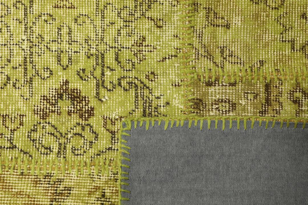 Een patchwork vloerkleed uit Turkije met een lichtgroen en bruin vintage design.