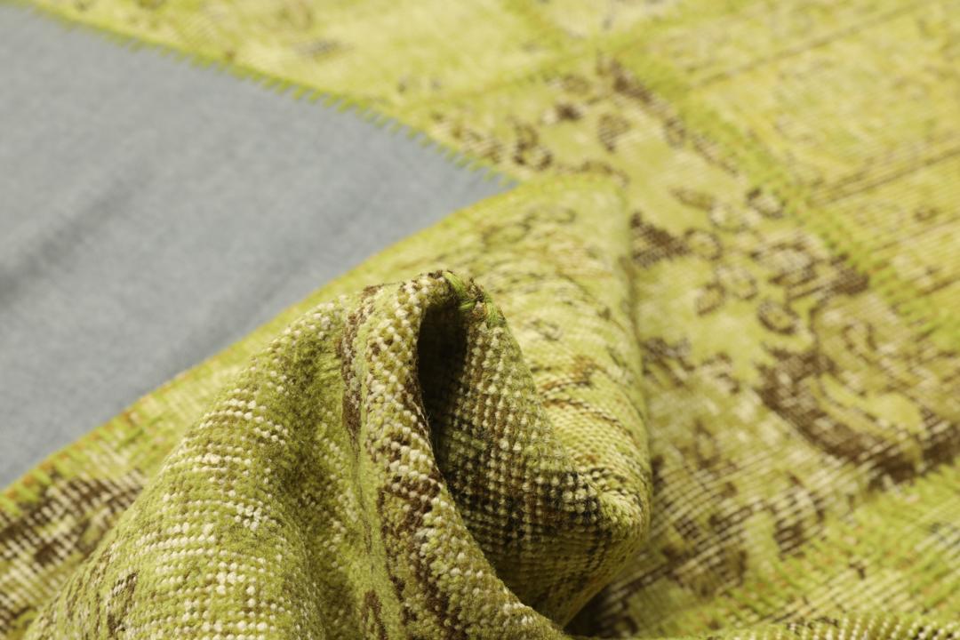 Een patchwork vloerkleed uit Turkije met een lichtgroen en bruin vintage design.