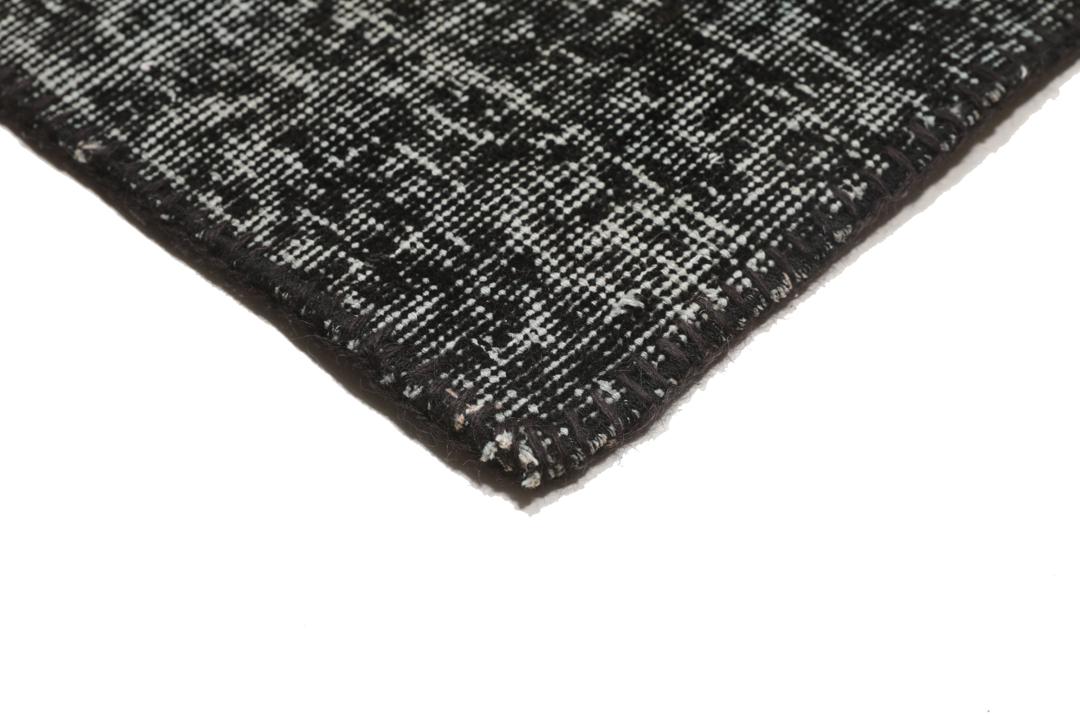 Een rechthoekig handgemaakt patchwork vloerkleed uit Turkije in zwarte en donkergrijze tinten.