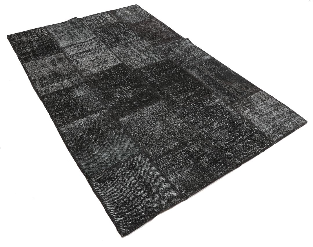 Een handgeknoopt Turks patchwork vloerkleed in diepzwarte tinten.