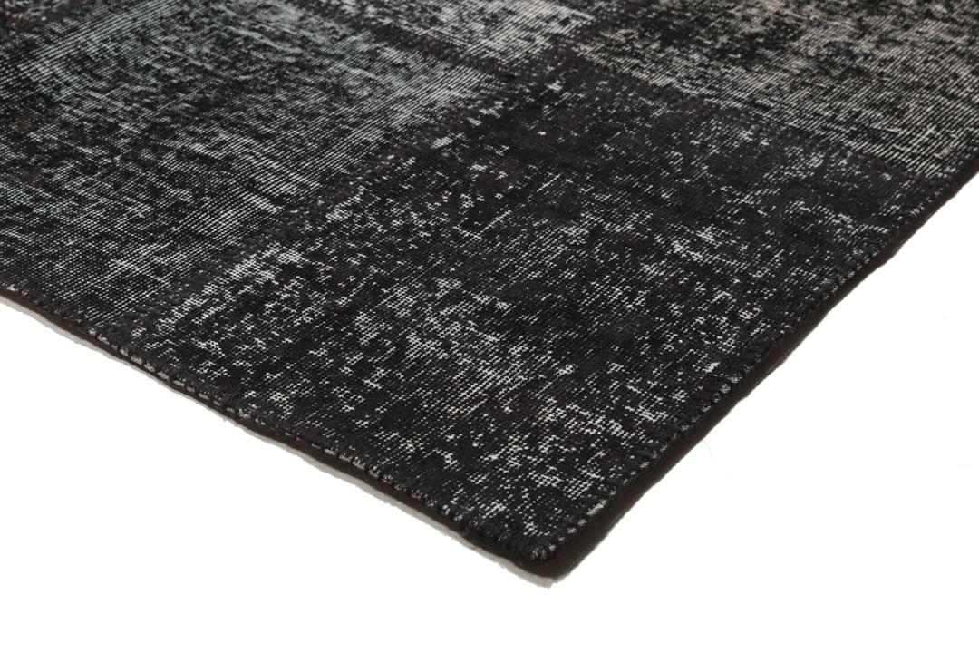 Een handgeknoopt Turks patchwork vloerkleed in diepzwarte tinten.