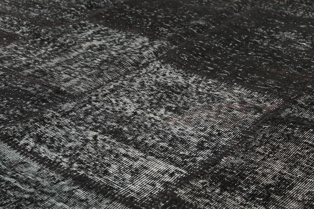 Een handgeknoopt Turks patchwork vloerkleed in diepzwarte tinten.