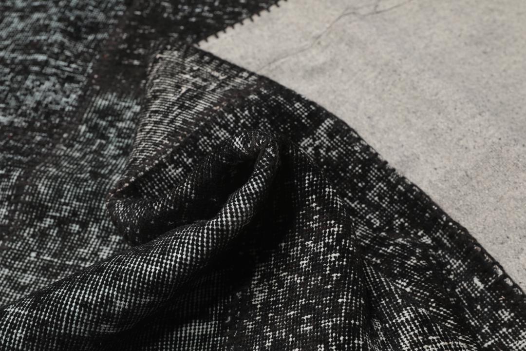 Een handgeknoopt Turks patchwork vloerkleed in diepzwarte tinten.